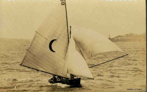 Postcard featuring a photograph of a skiff sailing on the water, with a crescent moon symbol on the raised sail