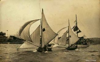 Postcard featuring a photograph of two skiffs sailing near land, with a masted vessel beside them