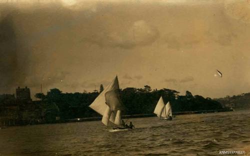 Postcard featuring a photograph of two skiffs sailing beside land