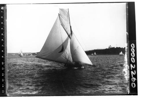 Yacht on Sydney Harbour, possibly DEFIANCE or KERIKI, displaying a crescent moon emblem on the mainsail