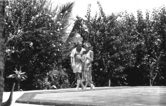 Photograph depicting a couple walking by a pool