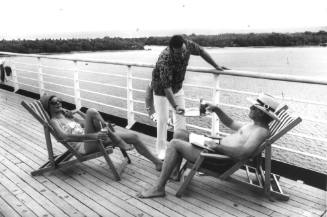 Photograph depicting a couple sunbathing on deck