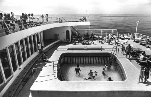 Photograph depicting passengers by the ship's pool