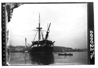 The former HMS / HMVS NELSON off Pyrmont, Sydney Harbour, with a rowing boat with two men visible nearby