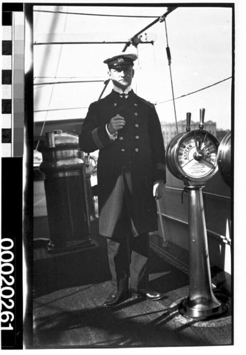 Captain from an English merchant steamship next to an engine order telegraph
