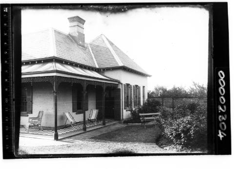 Single storey house with a verandah featuring a tiled floor, deckchairs and cane seat