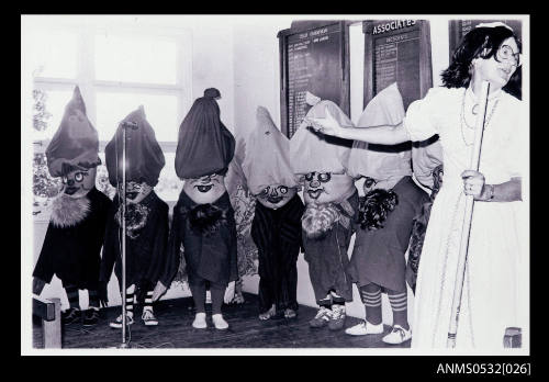 Children dressed in costumes, painted mask faces, large imitation beards, loose peaked caps, long jackets to knees