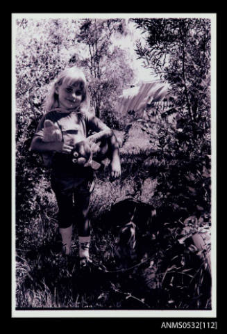 A young girl holding a monkey toy facing the camera