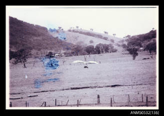 Hang glider flying over paddock