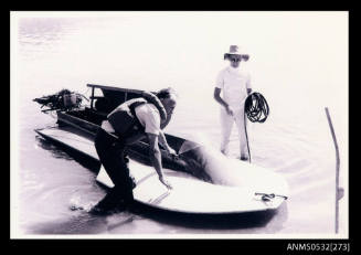 Man and woman with small hydroplane boat at water edge