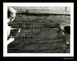 The two men caulking the timber planking of a boats hull