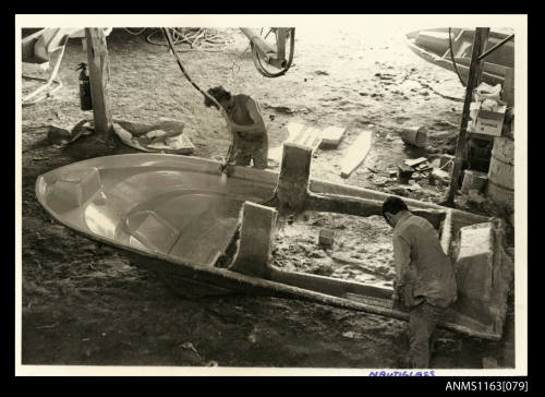 The two men working on the interior of a fibreglass boat hull