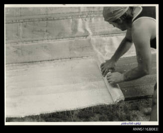 Men laying fibreglass matting inside boat hull