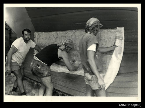 The view of three men placing fibreglass matting into a boat's keel area