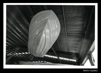 The view of fibre glass boat hull, suspended from overhead crane
