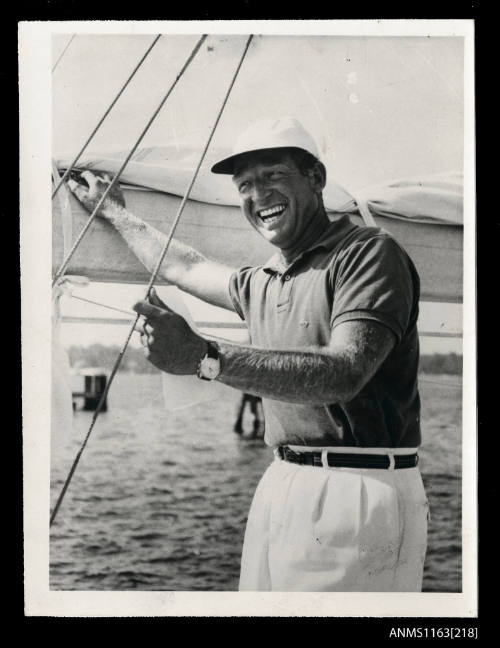 The man standing on a sailing vessel looking towards camera