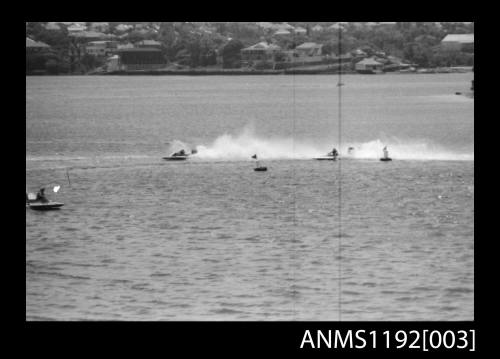 Two power boats at speed passing a marker buoy