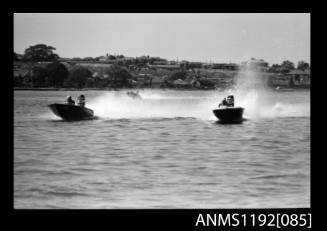 Black and white negative number 9 depicting three open power boats completing a turn, outboard engines at speed