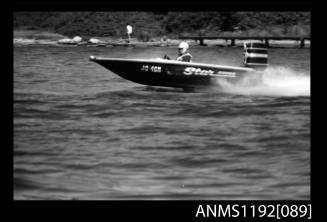 Black and white negative number 13 depicting open power boat STAR , Jo4on outboard engine at speed