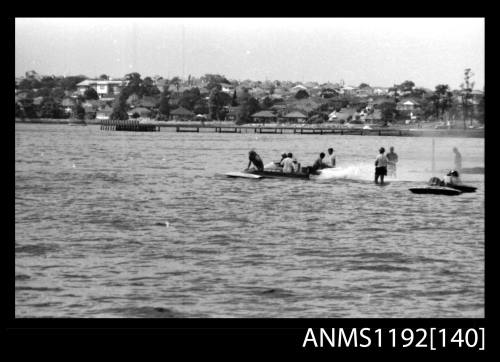 Black and white negative number 4 depicting two stationary power boats being prepared for racing