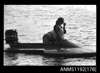 Black and white negative number 11 depicting power boat stationary, with woman in drivers seat