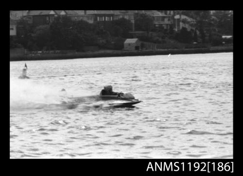 Black and white negative number 19 depicting power boat completing a turn at marker buoy