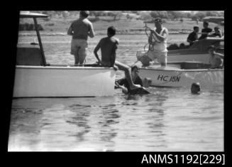Black and white negative number 1A depicting two men in the water between the stern of two power boats, including Hc15n At Stuart Doyle Gold Cup in New South Wales