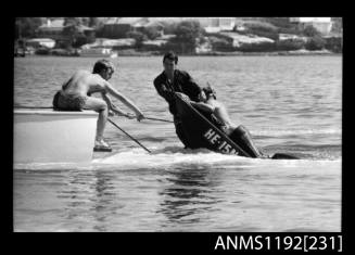 Black and white negative number 3 depicting man hanging on to a rope which is towing the sunken He15n