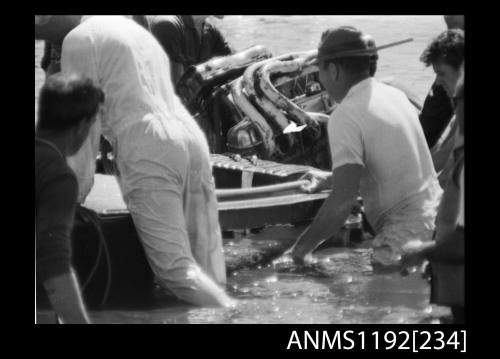 Black and white negative number 6 depicting He15n Power boat, damaged from sinking and being pushed ashore at Stuart Doyle Gold Cup in New South Wales