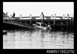 Black and white negative number 3A depicting Lorri half cabin power boat with outboard engine on boat ramp