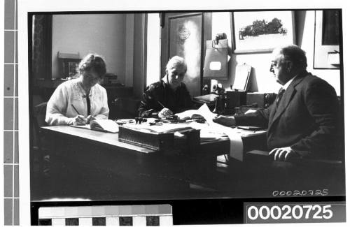 An unidentified man and two women seated at a table