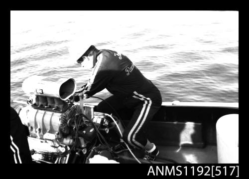 Black and white negative number 4 depicting view of man working on a v-8 petrol inboard engine of S k