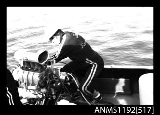 Black and white negative number 4 depicting view of man working on a v-8 petrol inboard engine of S k