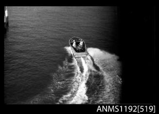 Black and white negative number 6 depicting view of power boat with inboard engine, driver and co-driver, at speed