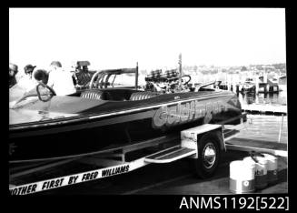 Black and white negative number 3 depicting view of GOLDFINGER Power boat with inboard v-8 engine on its road trailer, port quarter view