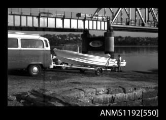 Black and white negative number 6A depicting view of open power boat on its road trailer behind v