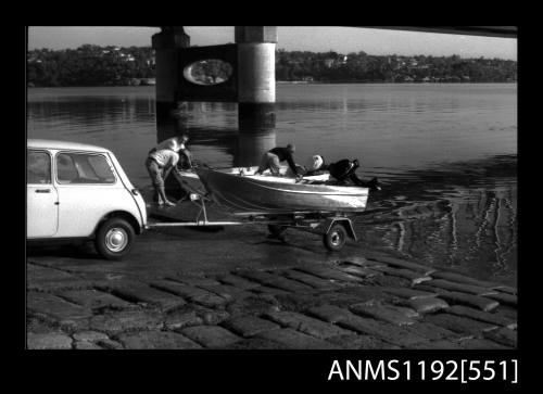 Black and white negative number 7A depicting view of open power boat on its road trailer behind MINI minor