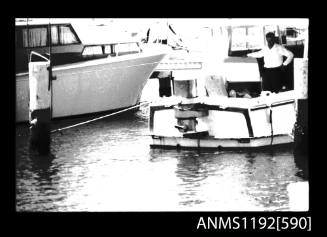 Black and white negative number 13 depicting view of boiler mounted outboard on transome of motor cruiser, stern/ starboard side view, from jetty / boat