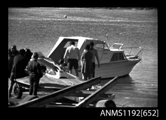 Black and white negative number 7A depicting view of MISS DURRAS OZ59N cabin cruiser sharing a boat ramp with a hydroplane on its trailer