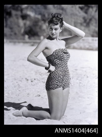 Swimsuit model kneeling on a beach