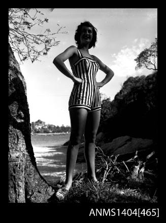 Photographic negative of swimsuit model standing on a scrubby shore