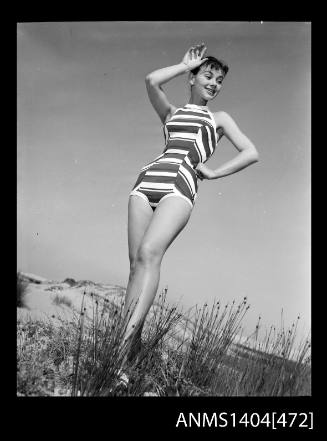 Photographic negative of swimsuit model posing on a sand dune
