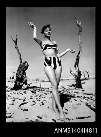 Photographic negative of swimsuit model posing on a beach in a bikini