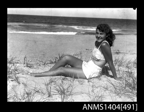 Photographic negative of swimsuit model posing on a beach