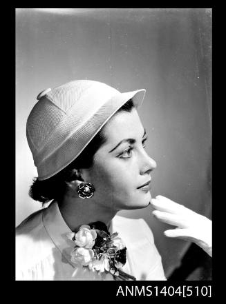 Photographic negative of a model posing with a hat and posy of flowers