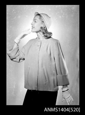 Photographic negative of a model posing in a coat and hat