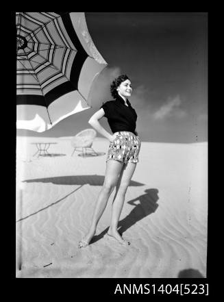 Photographic negative of a model posing in casual wear on a beach