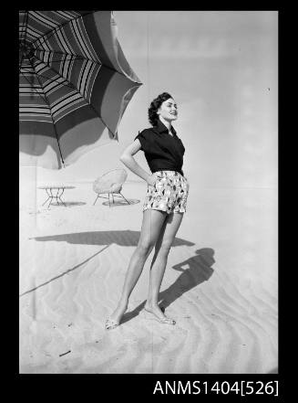 Photographic negative of a model posing in casual wear on a beach