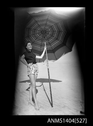 Photographic negative of a model posing in casual wear on a beach