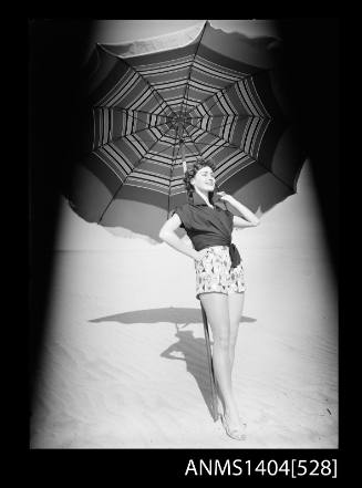 Photographic negative of a model posing in casual wear on a beach